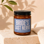Amber candle in glass jar with black lid, label says "Bride's Last Nerve".