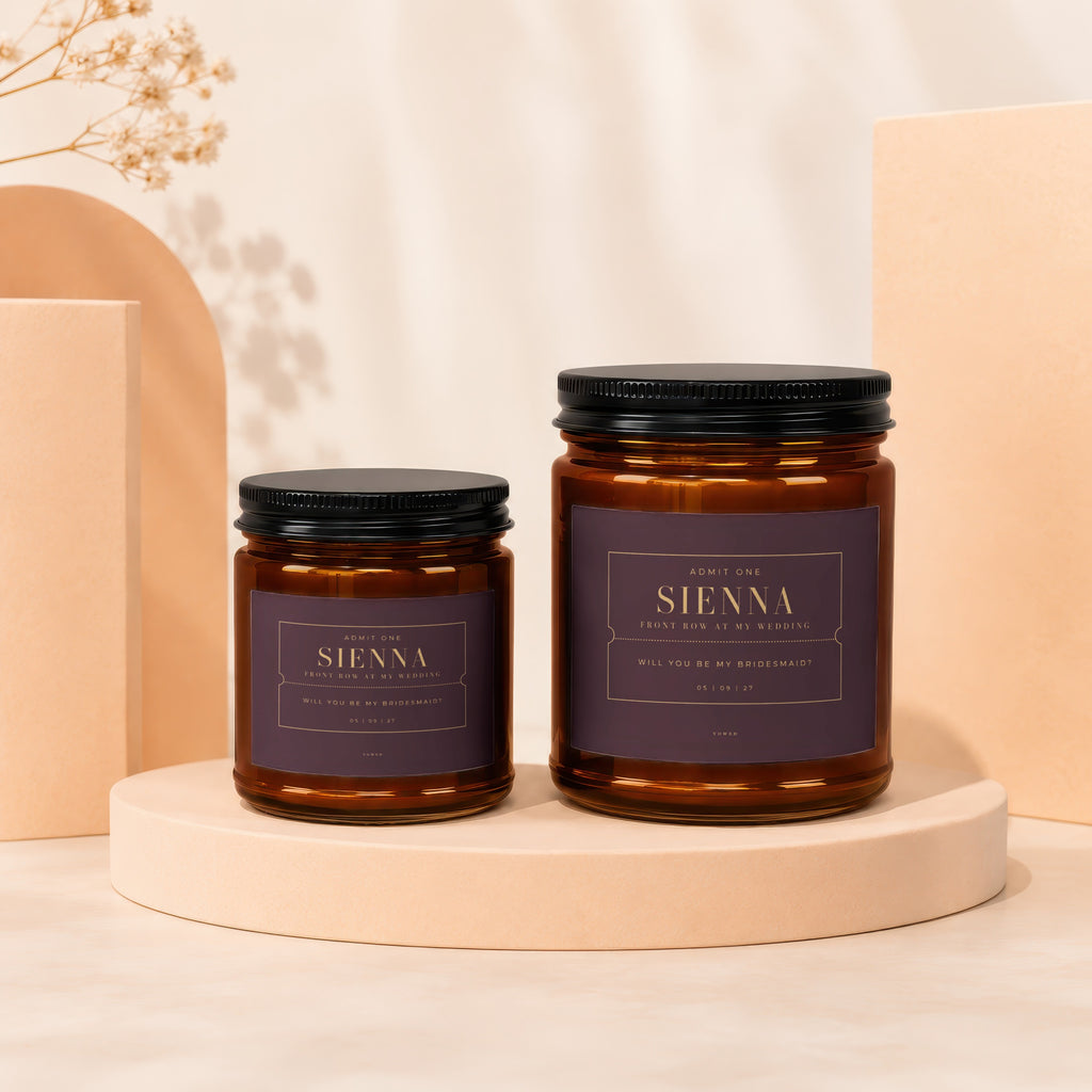 Two amber glass candles with purple labels asking "Will you be my bridesmaid?".
