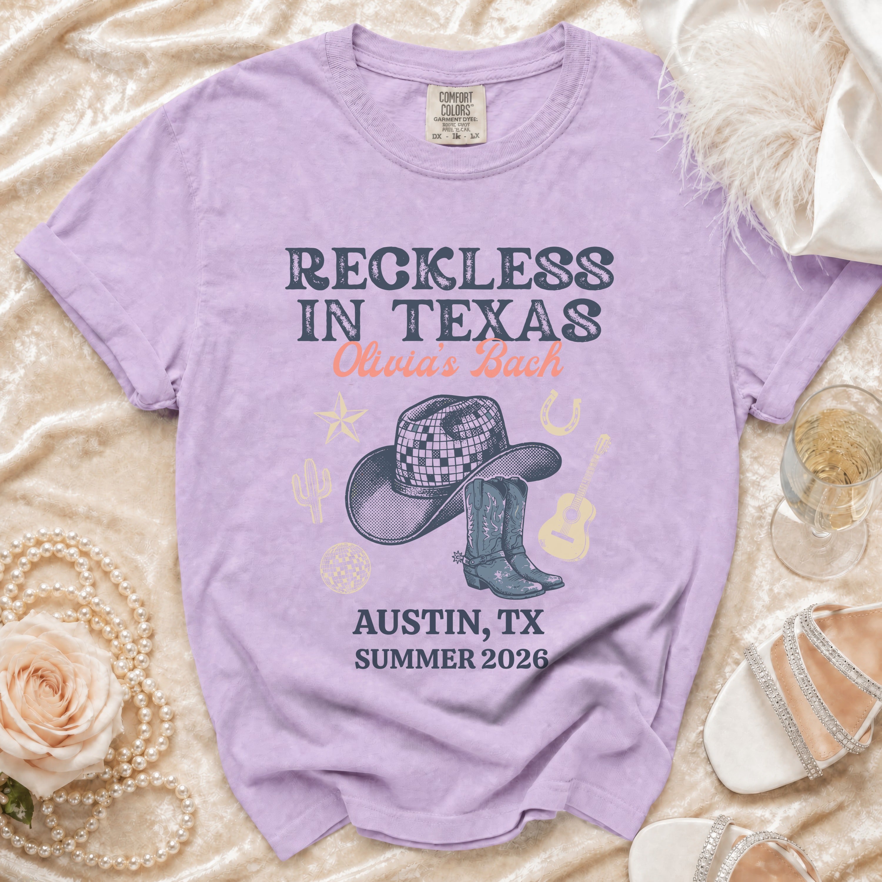 Purple t-shirt with "Reckless in Texas Olivia's Bach Austin, TX Summer 2026" graphic.