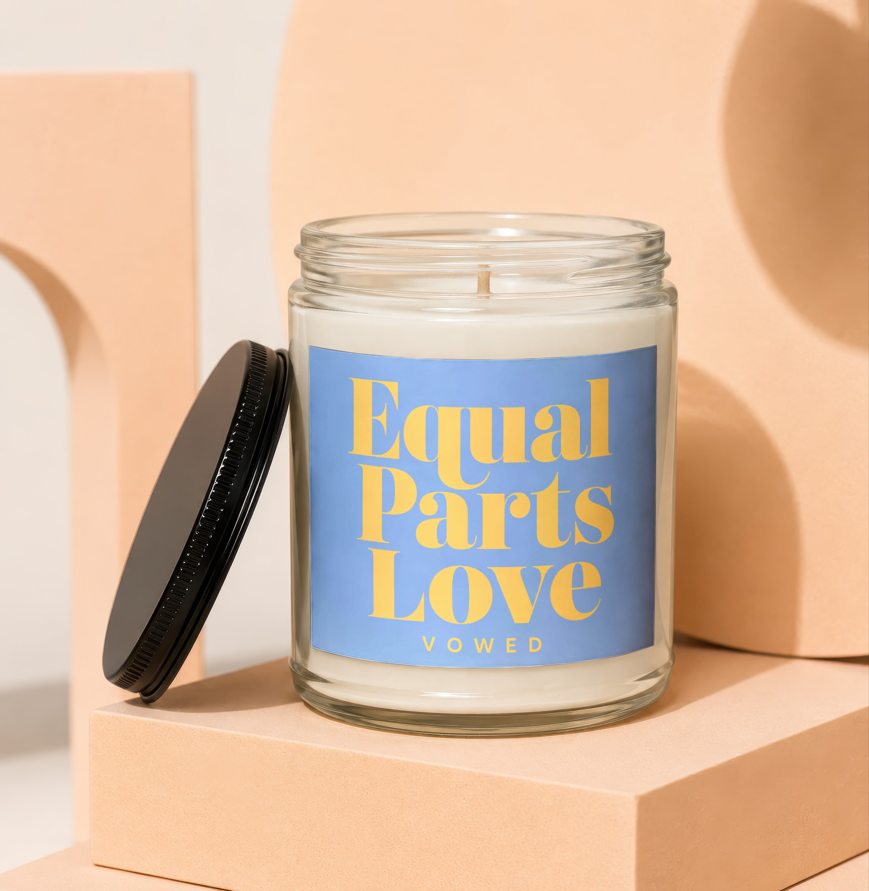 Candle with "Equal Parts Love" and "VOWED" text on a blue label.