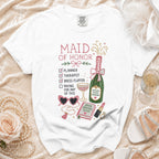 White t-shirt with "Maid of Honor" checklist, champagne bottle, and party accessories graphic.