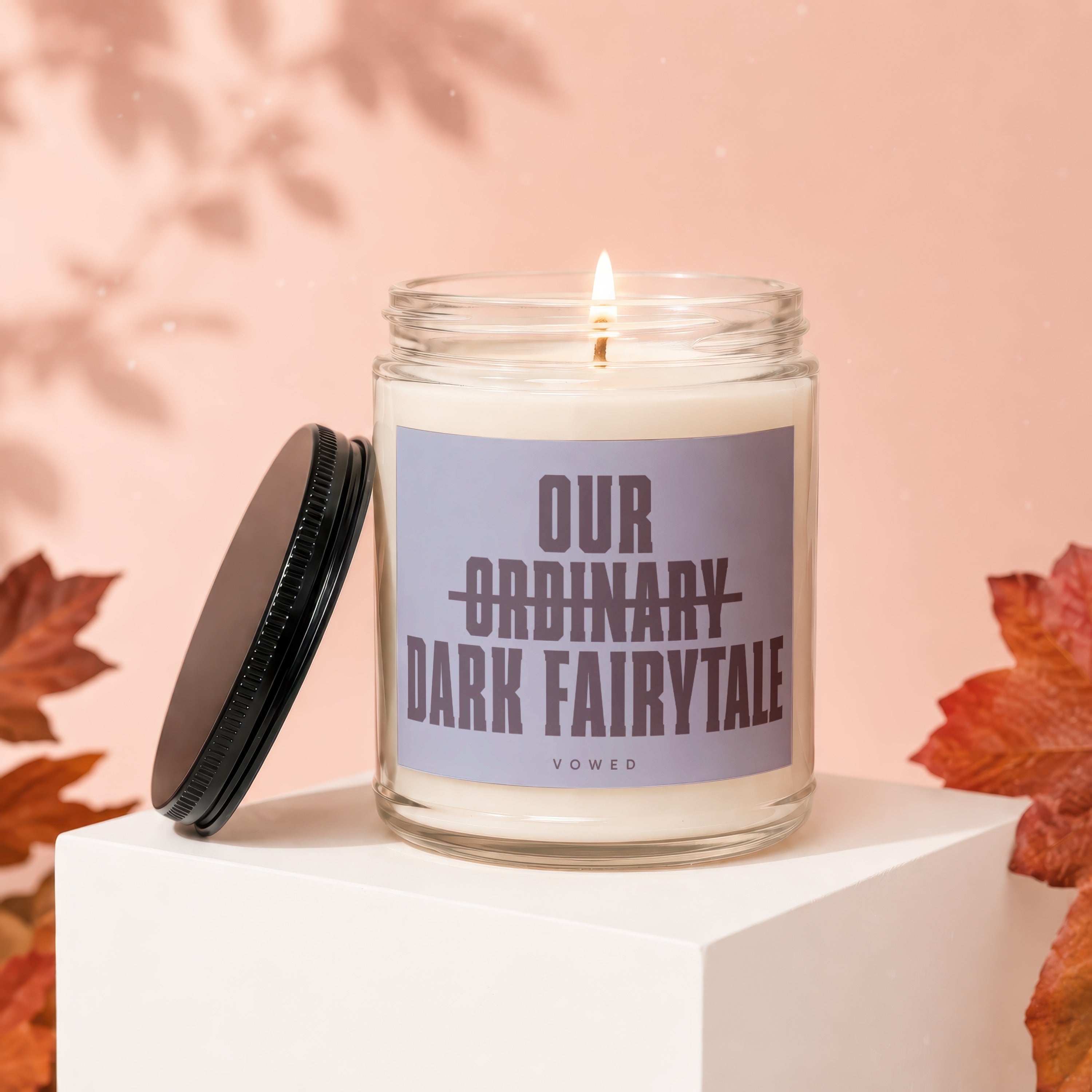 Glass jar candle with lid off, labeled "OUR ORDINARY DARK FAIRYTALE"