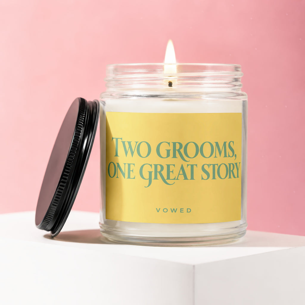 Burning candle in glass jar with yellow label that reads "Two Grooms, One Great Story VOWED".