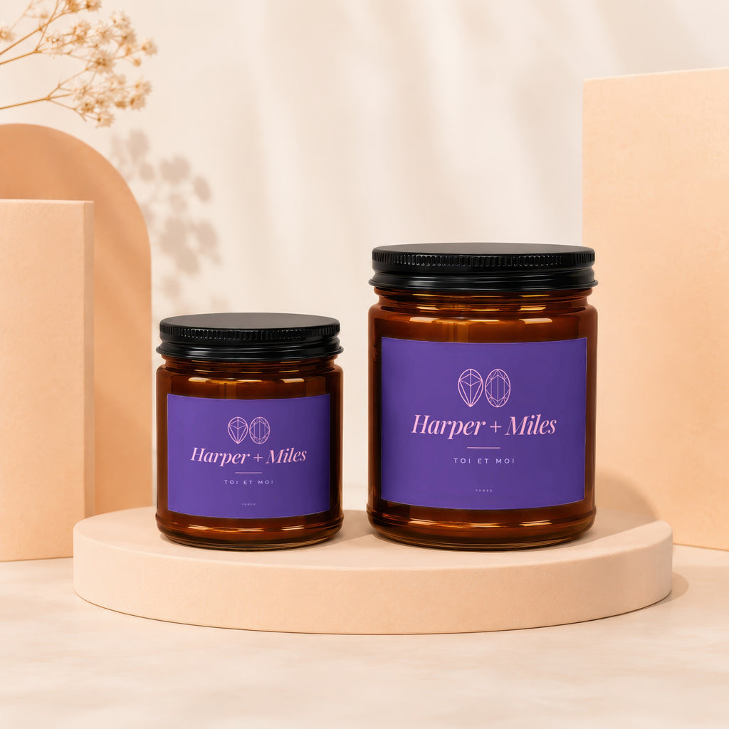 Two amber glass candles with purple labels reading "Harper + Miles" and "Toi et Moi".