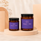 Two amber glass candles with purple labels reading "Harper + Miles" and "Toi et Moi".