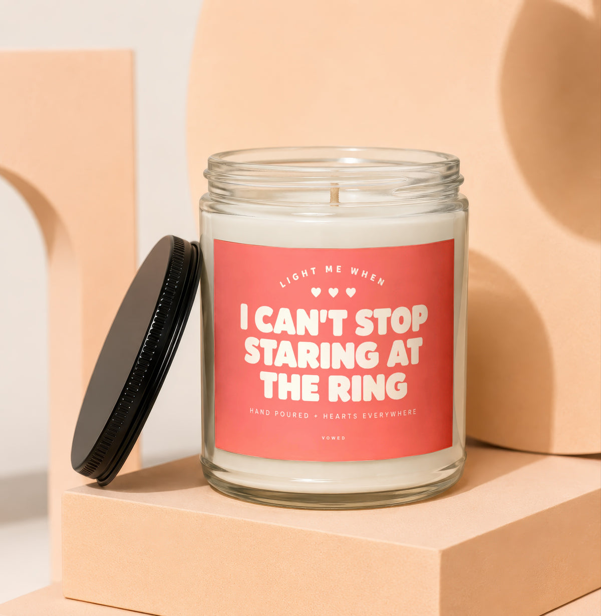 Glass candle with pink label reading "I can't stop staring at the ring."