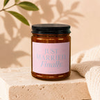 Amber candle jar with black lid, reads "JUST MARRIED. Finally. VOWED".