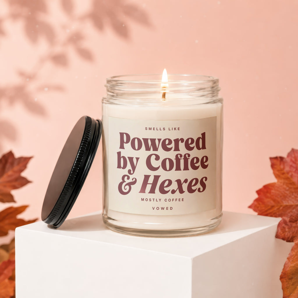 Candle with lit wick on white pedestal, labeled "Powered by Coffee & Hexes".