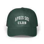 A dark green baseball cap featuring the white embroidered text APRES SKI CLUB across the front.