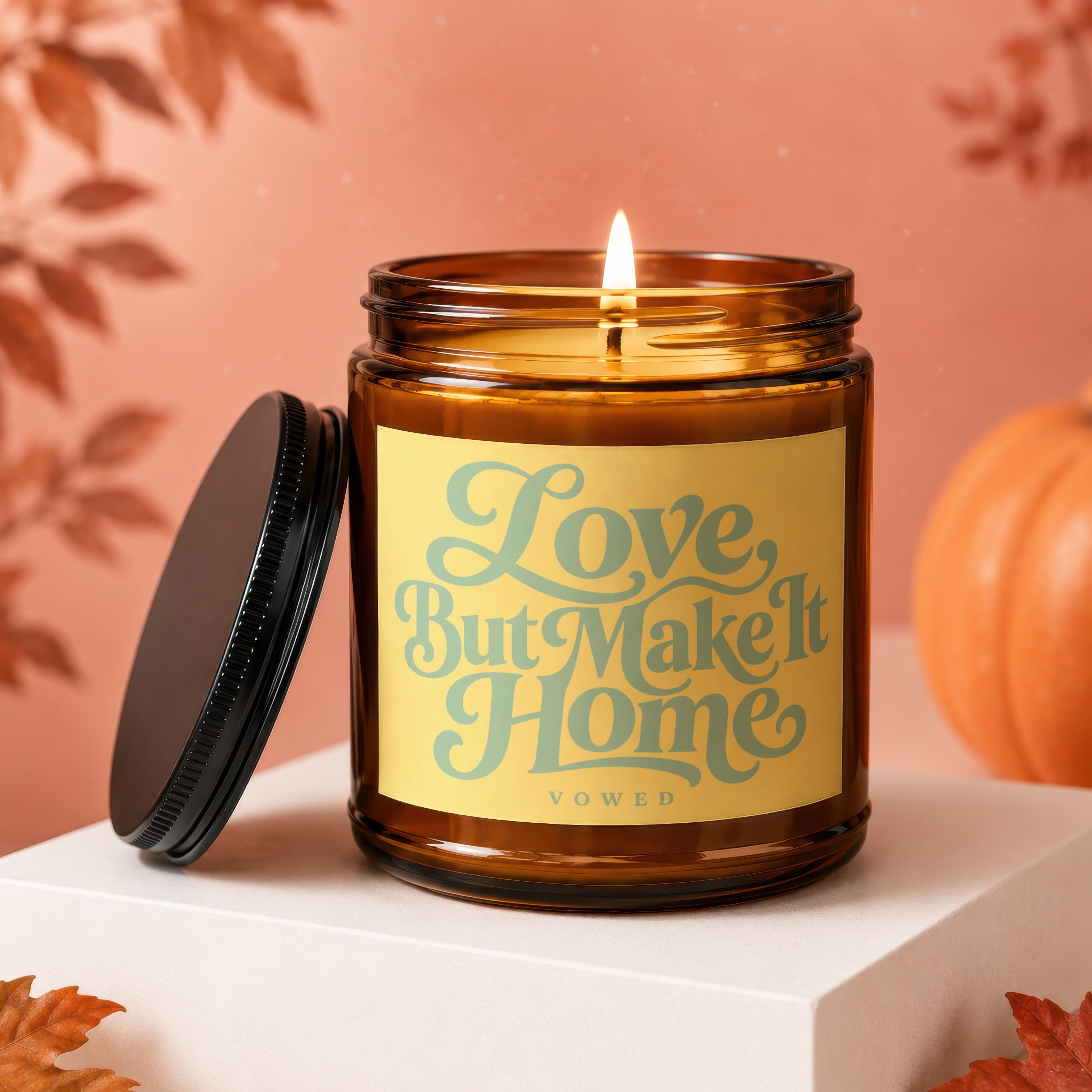 Amber jar candle with lid off, "Love But Make It Home Vowed" text.