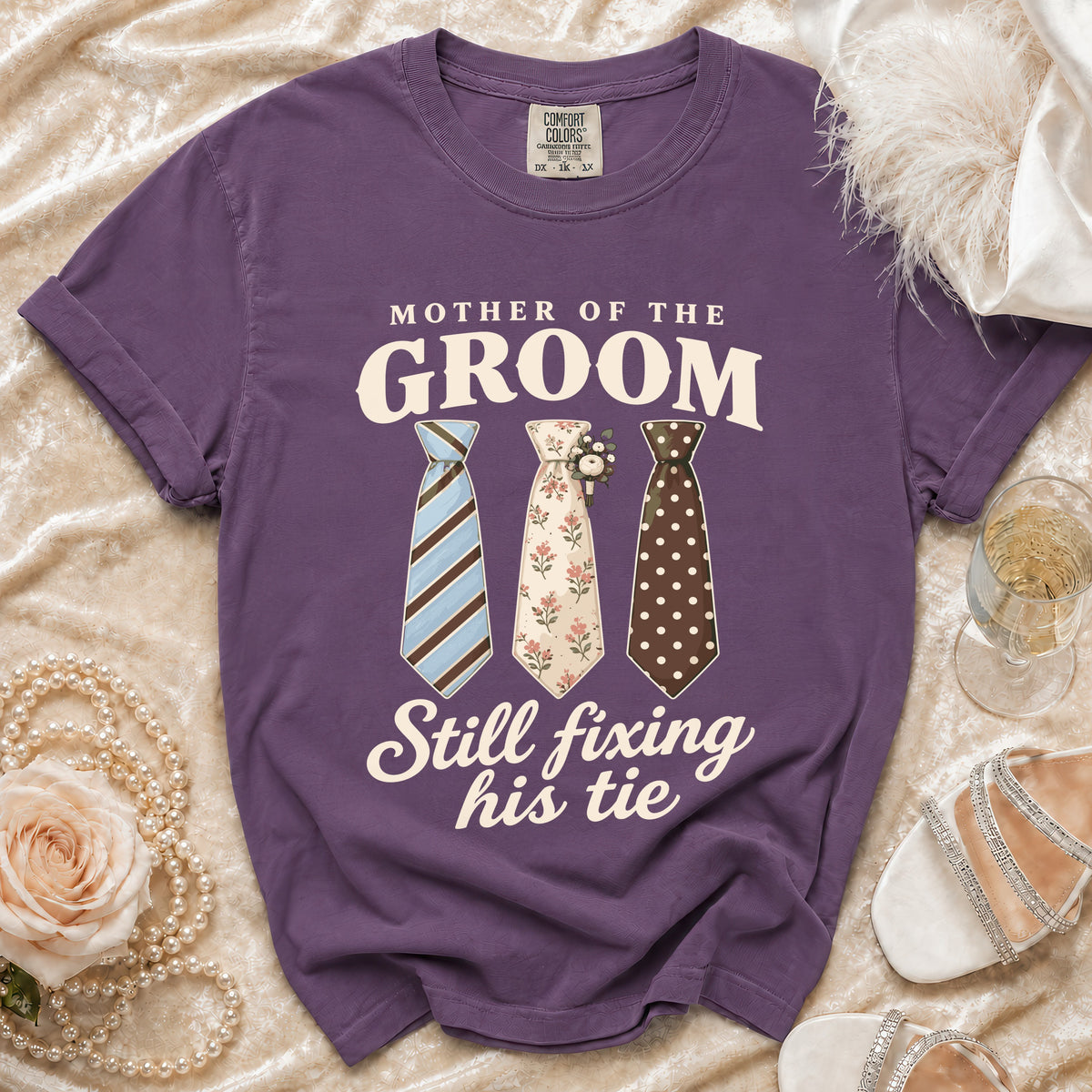 Purple t-shirt with "Mother of the Groom Still Fixing His Tie" and three ties.