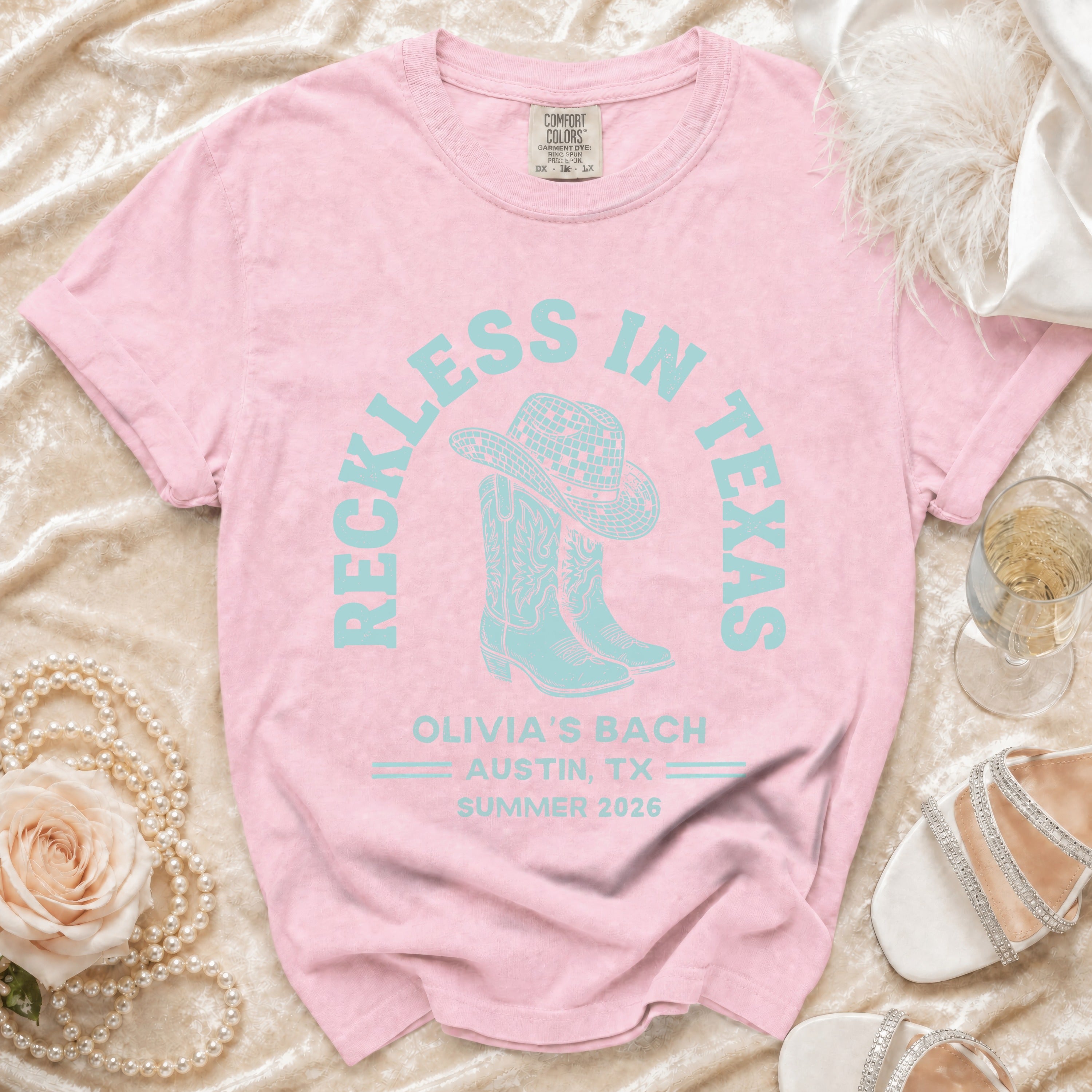 Light pink t-shirt with "Reckless in Texas" and "Olivia's Bach Austin, TX Summer 2026" text.