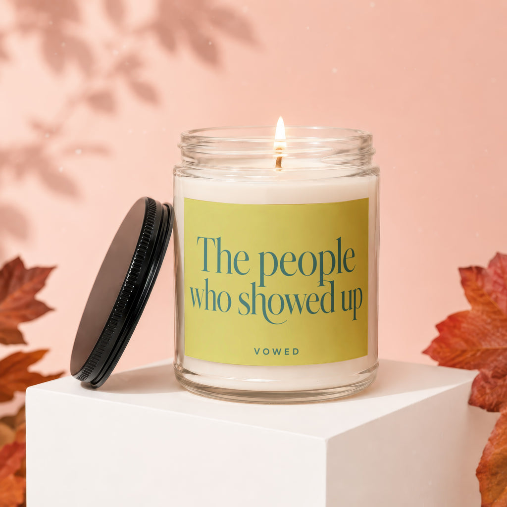 Burning candle in glass jar with "The people who showed up" text and lid.