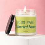Lit candle in glass jar with green label reading "HOME SWEET Married Home VOWED".
