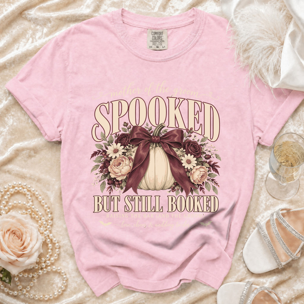 Pink Comfort Colors t-shirt with "mother of the groom SPOOKED BUT STILL BOOKED" graphic.