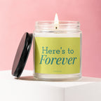 Glass candle with burning wick and "Here's to Forever" Vowed label.