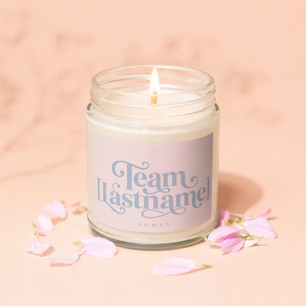 Lit candle with "Team Lastname Vowed" on label, surrounded by pink petals.