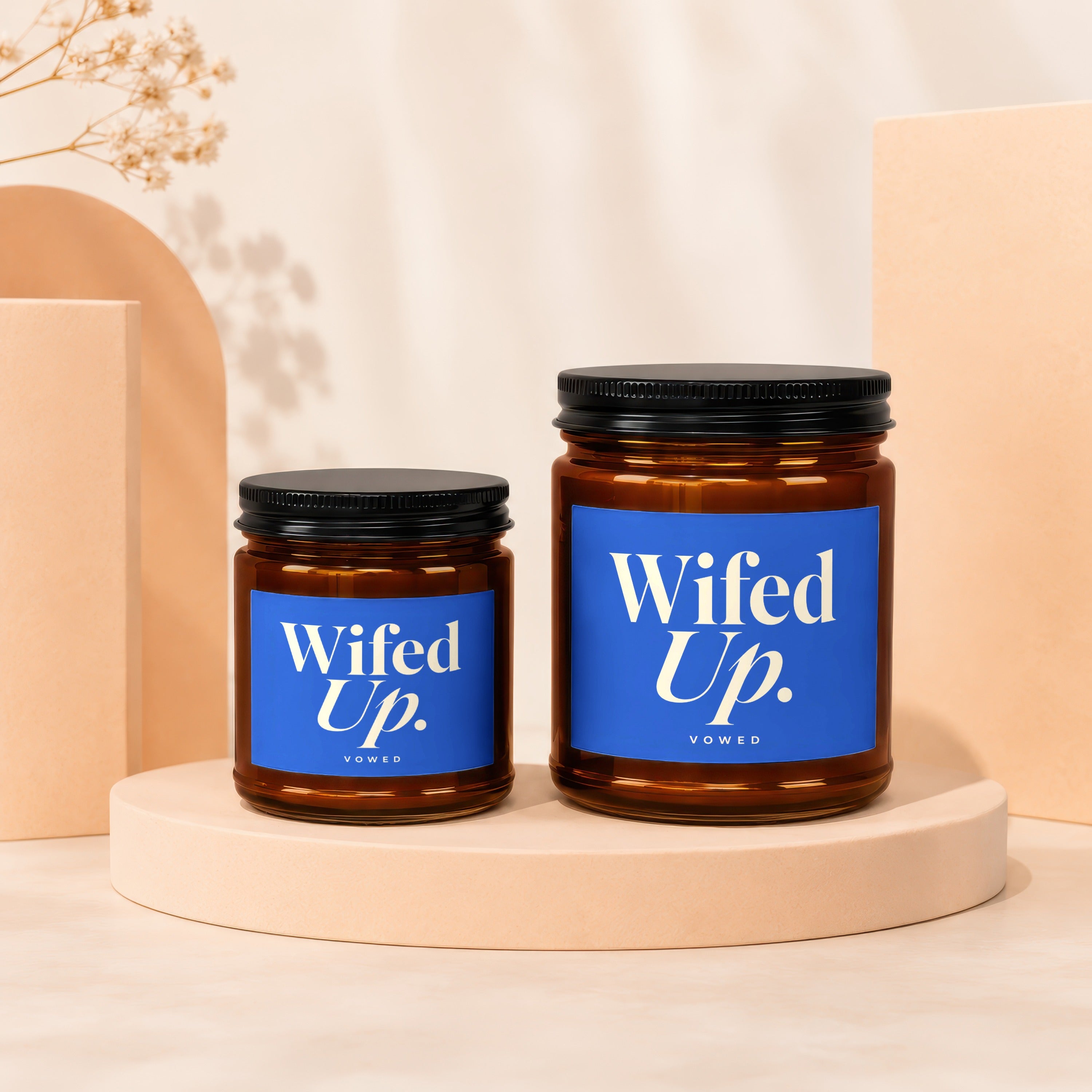 Two amber glass candles with black lids and blue "Wifed Up." labels.