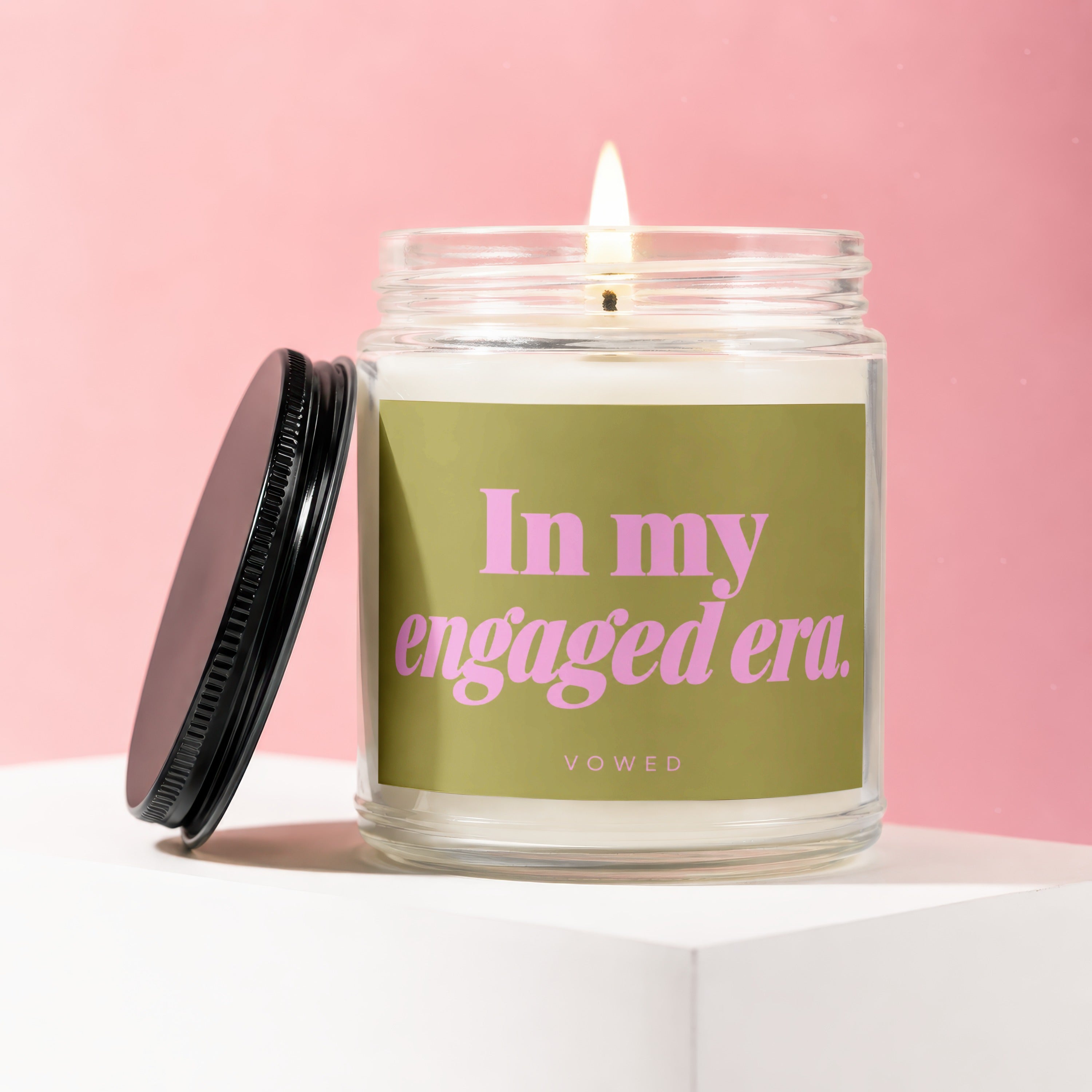 Lit candle in glass jar with lid off, reads "In my engaged era. VOWED".