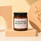 Amber glass candle with a black lid and a pink label that reads "to the friend who never left".