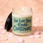Glass candle with lit wick, label reads "Our Love Story Ends Continues"