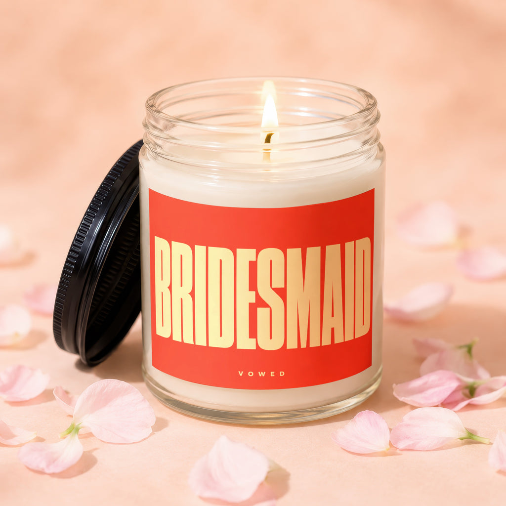 Glass jar candle with a red label reading "BRIDESMAID VO WED".