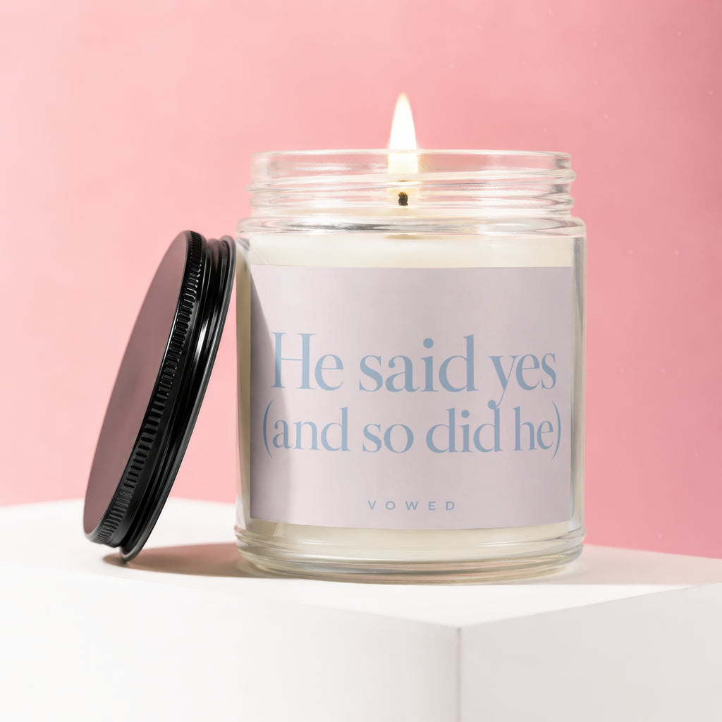 Jar candle with a lit wick and a label reading "He said yes (and so did he)"