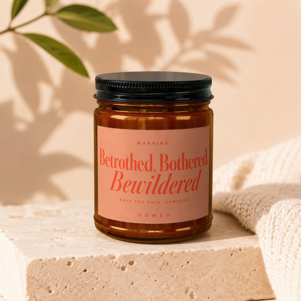 Amber jar candle with black lid labeled "Betrothed, Bothered, Bewildered."