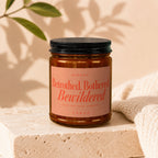 Amber jar candle with black lid labeled "Betrothed, Bothered, Bewildered."