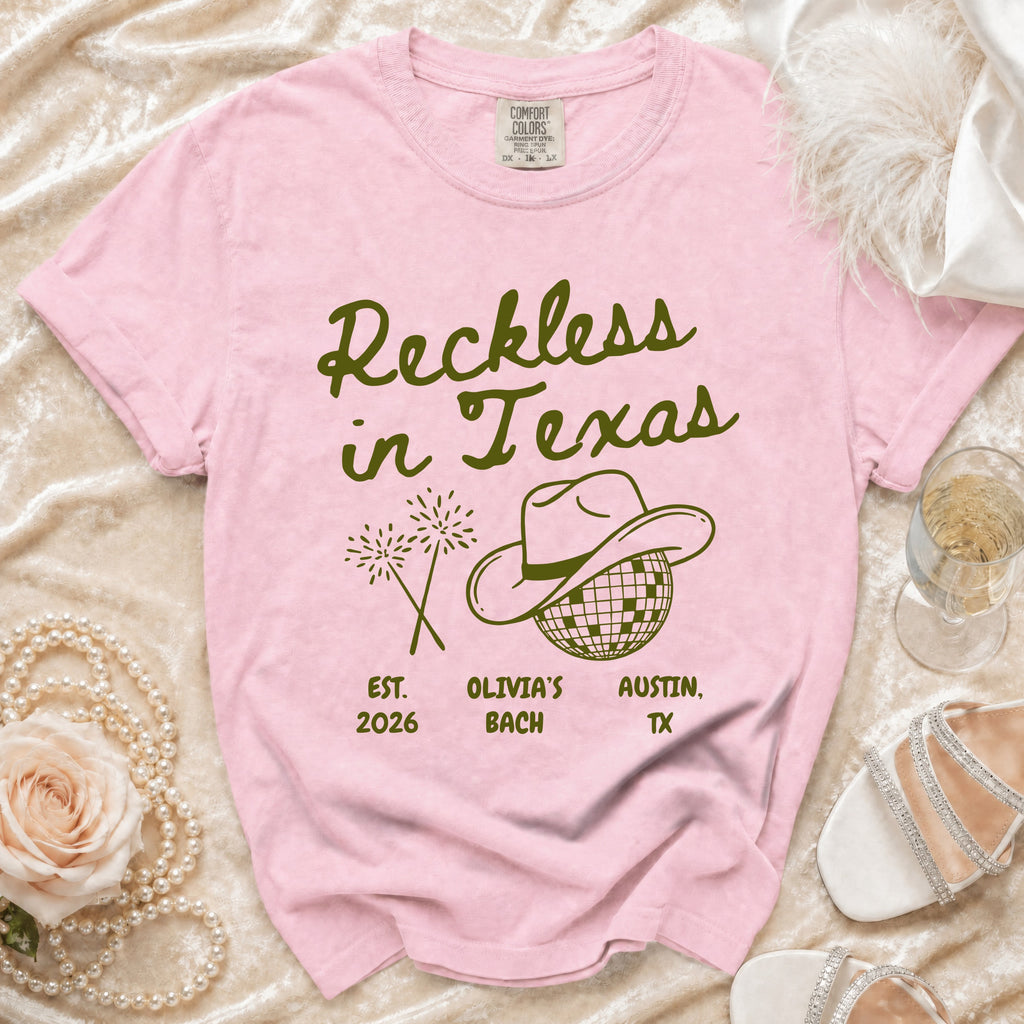 Pink t-shirt with "Reckless in Texas" and cowboy hat graphic.