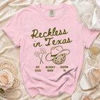 Pink t-shirt with "Reckless in Texas" and cowboy hat graphic.