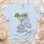Light blue t-shirt with a graphics of a margarita and text "This Girl Needs a Margarita".