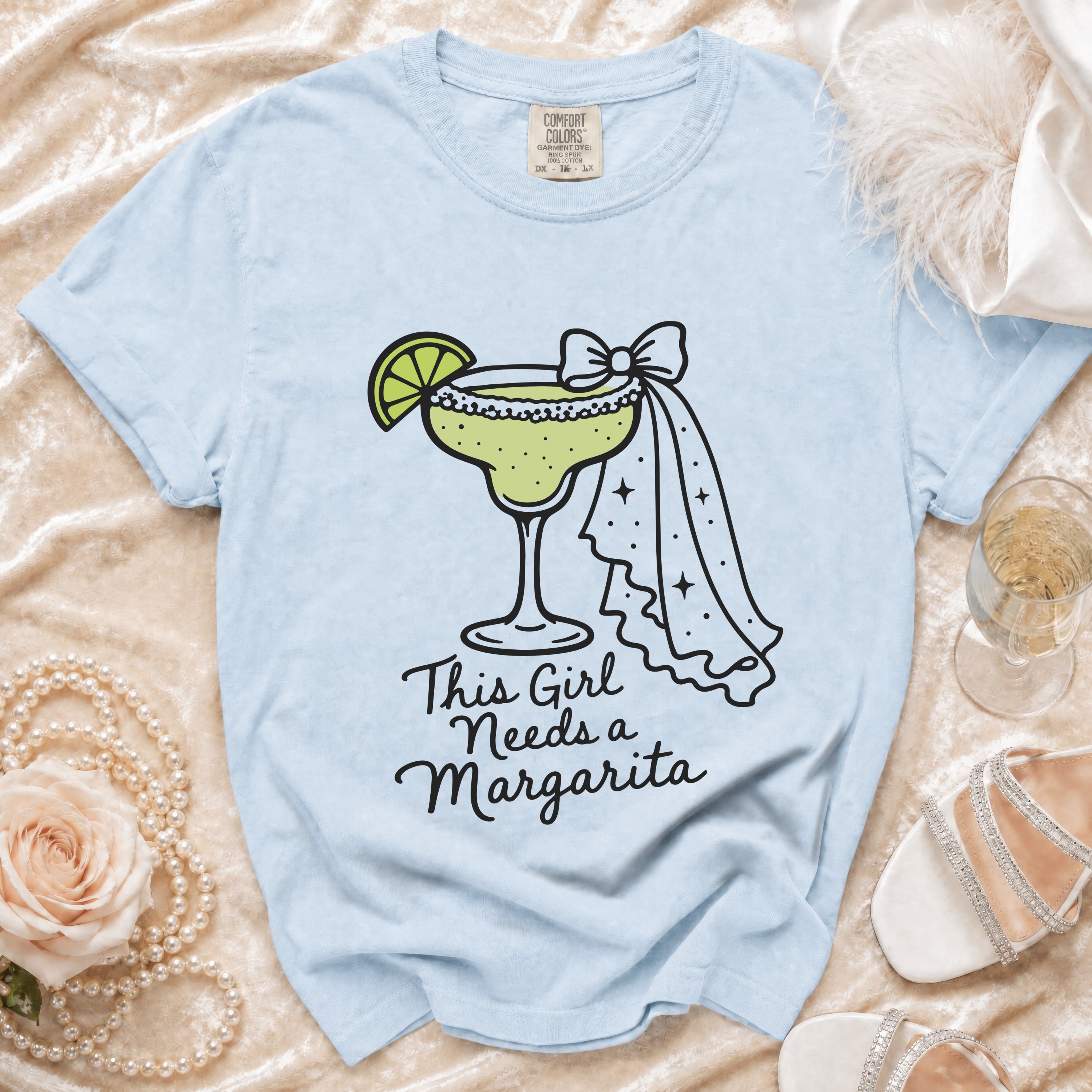 Light blue t-shirt with a graphics of a margarita and text "This Girl Needs a Margarita".