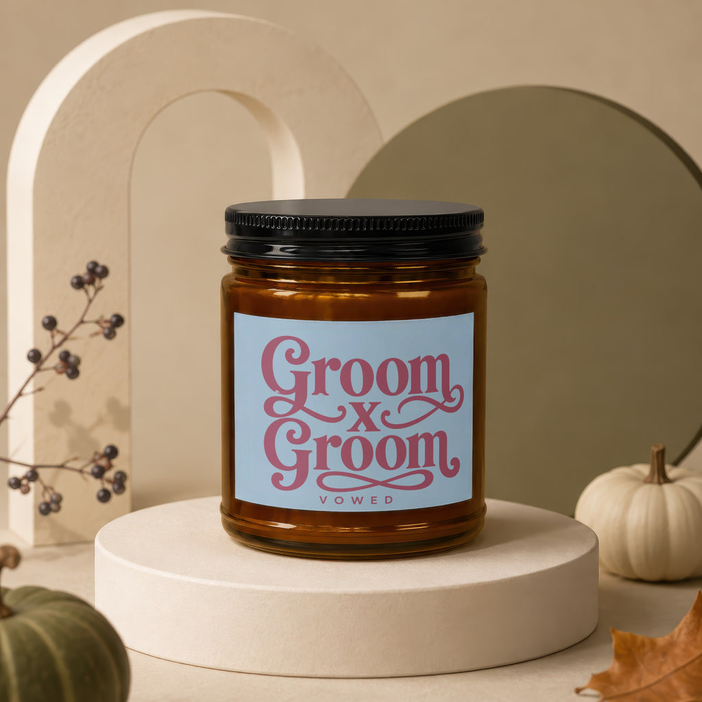 Groom X Groom Vowed candle in amber jar with black lid and light blue label.