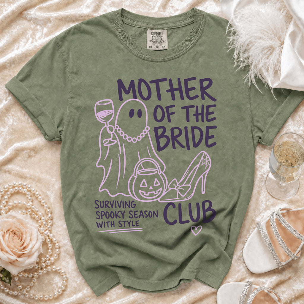 Green t-shirt with purple text and graphics reading "MOTHER OF THE BRIDE" and "SURVIVING SPOOKY SEASON WITH STYLE".