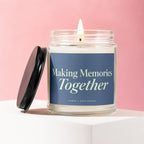 Glass candle with lit flame and navy blue label reading "Making Memories Together".