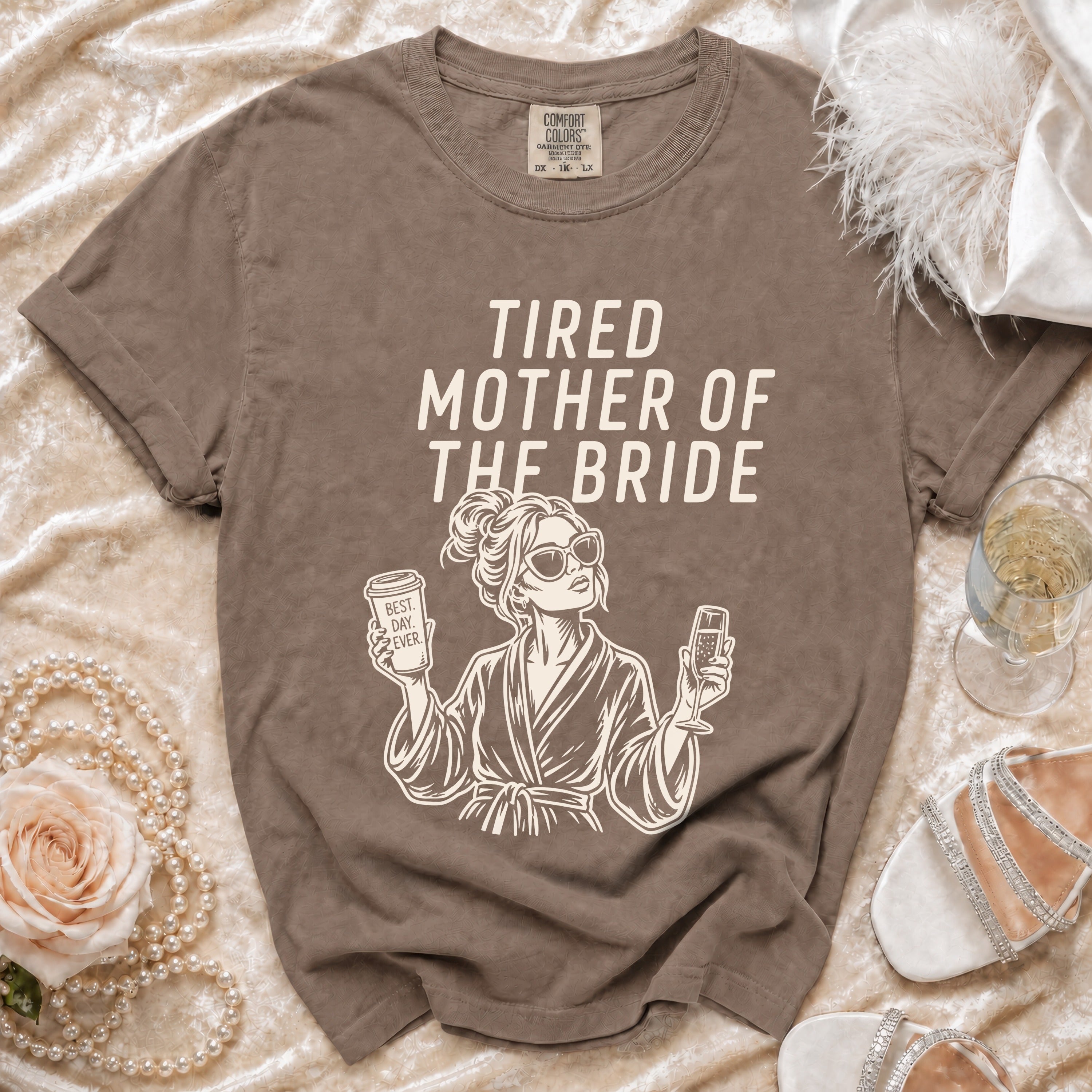 T-shirt with "Tired Mother of the Bride" text and graphic, surrounded by decorative items.
