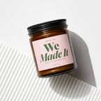 Amber jar candle with pink label reading "Smells Like We Made It"