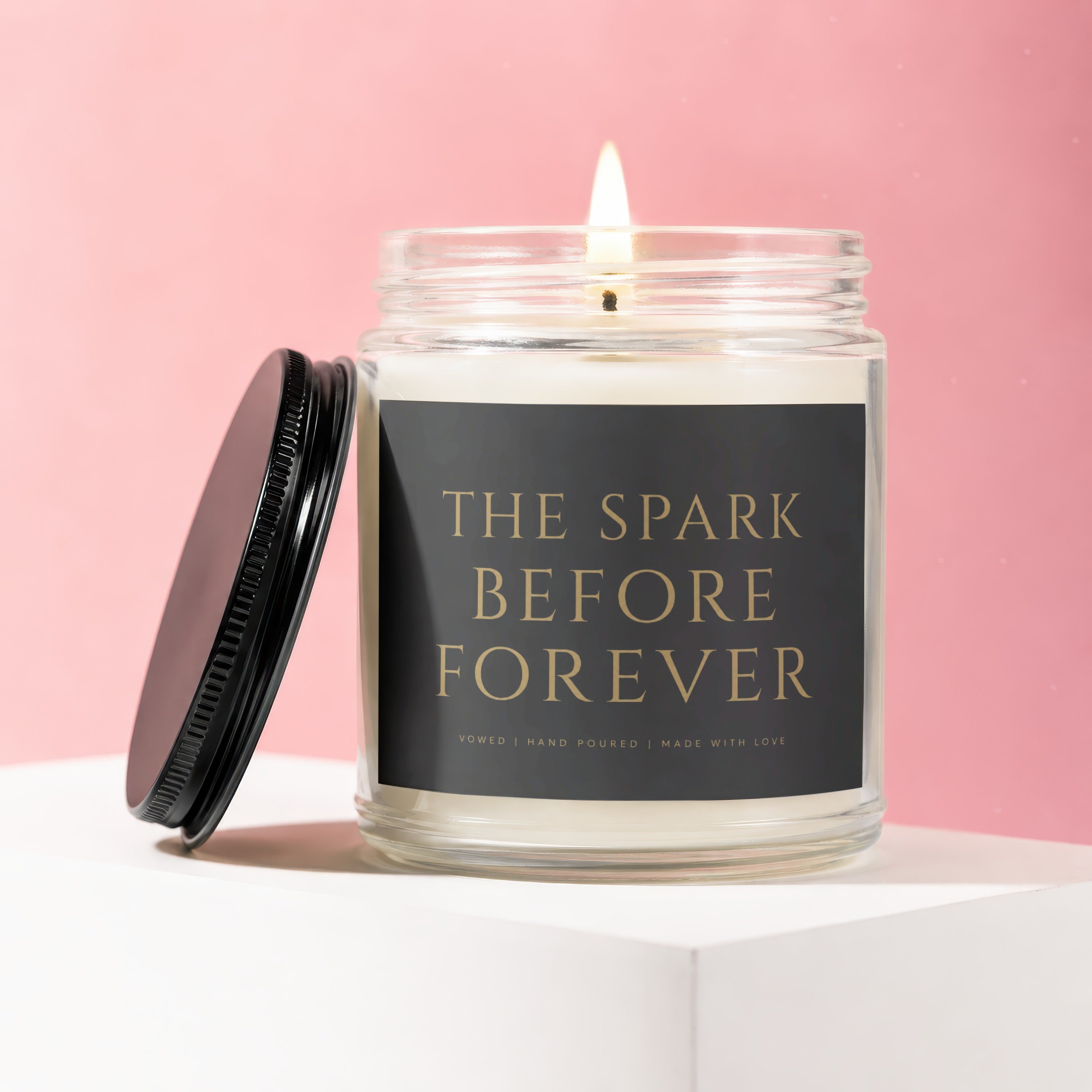 Candle with lid off, lit flame, and label "The Spark Before Forever."