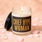 Glass candle with lit wick and "Chief Hype Woman" label, surrounded by pink petals.