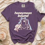 Purple t-shirt with "honeymoon bound" text and graphic of suitcases, hat, and ribbon.