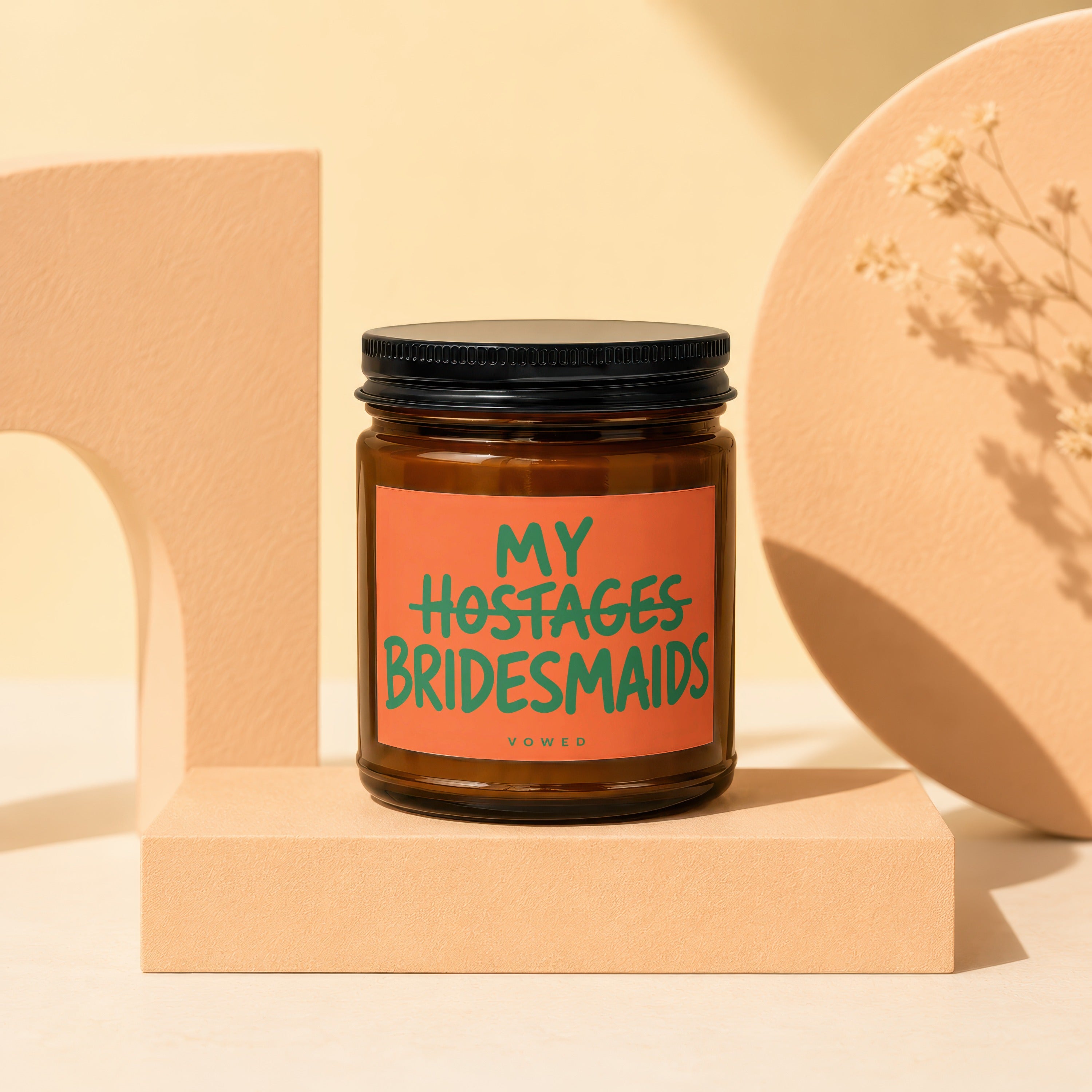 Amber jar candle with orange label reading "MY HOSTAGES BRIDESMAIDS" and "VOWED".