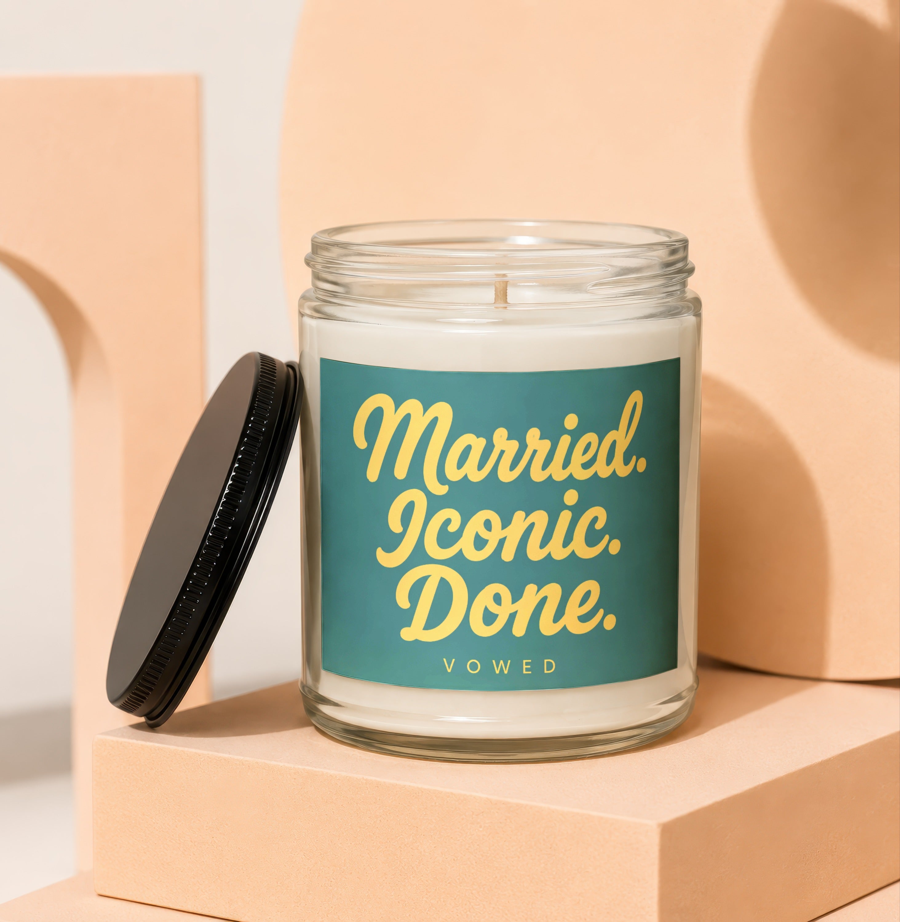Glass candle with teal label reading "Married. Iconic. Done. VOWED."