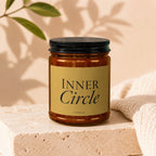 Amber glass jar candle with black lid, gold label reads "INNER Circle VOWED".