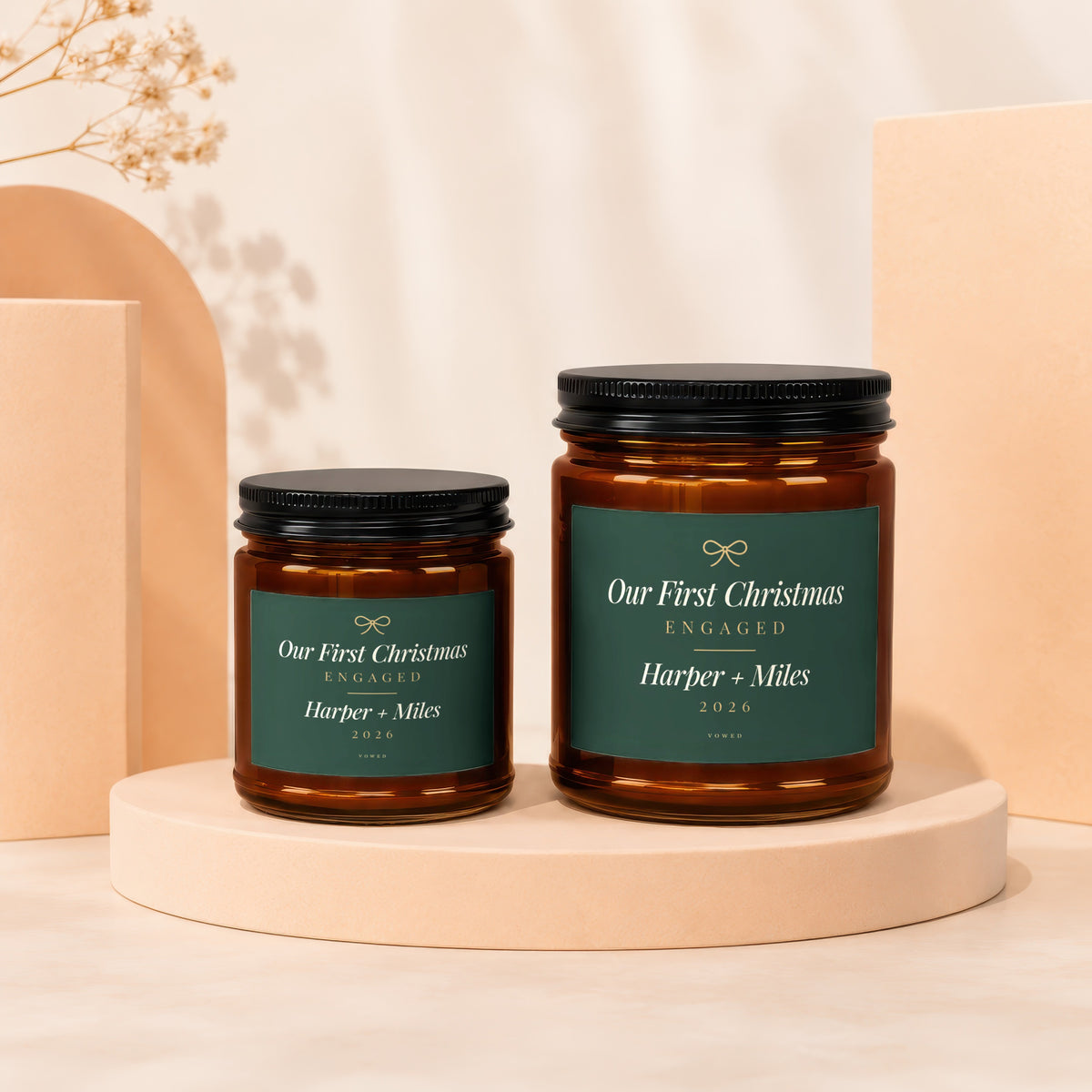 Two amber glass candles labeled "Our First Christmas Engaged Harper + Miles 2026".