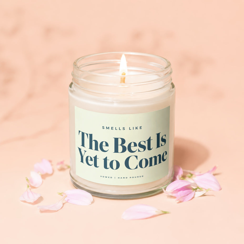 Candle with text "The Best Is Yet to Come", surrounded by petals.