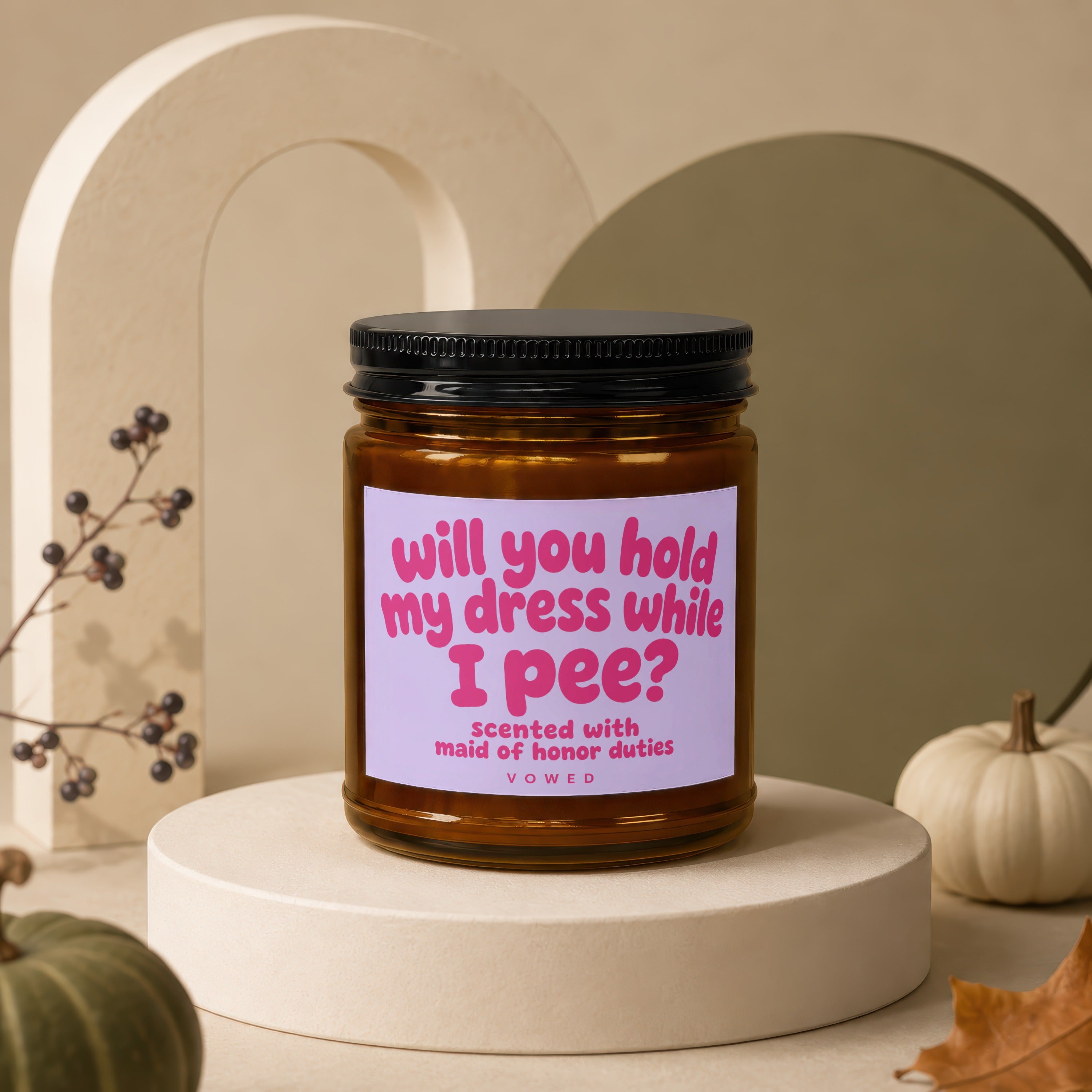 Amber jar candle with black lid labeled "Will you hold my dress while I pee?"