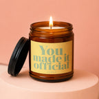 Amber jar candle with lit flame, reads "You made it official VOWED".
