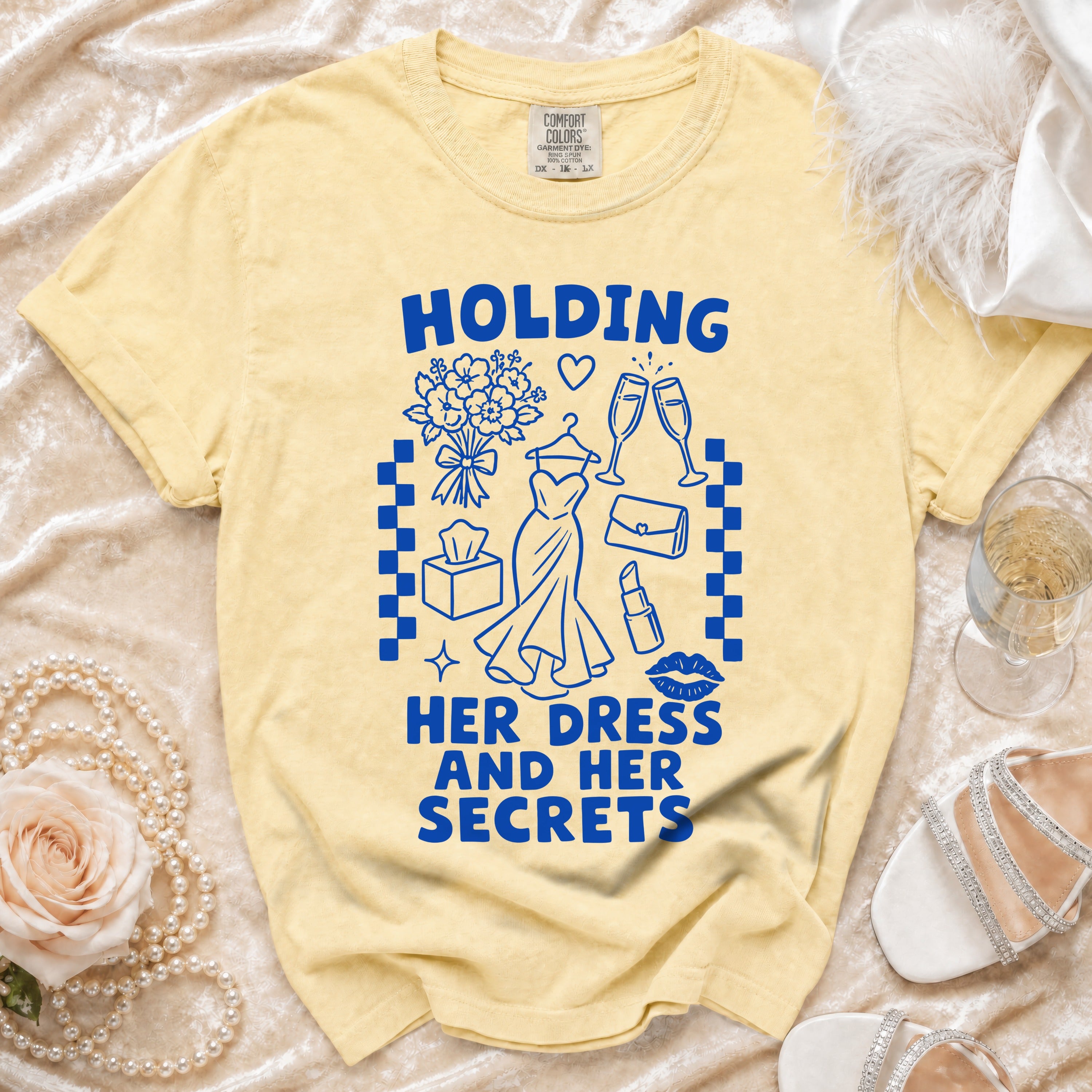 Yellow t-shirt with blue graphic: "HOLDING HER DRESS AND HER SECRETS"