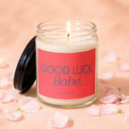 Candle with "GOOD LUCK, Babe." text on a pink label, surrounded by flower petals.